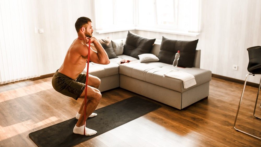 a photo of a man using a resistance band to workout at home