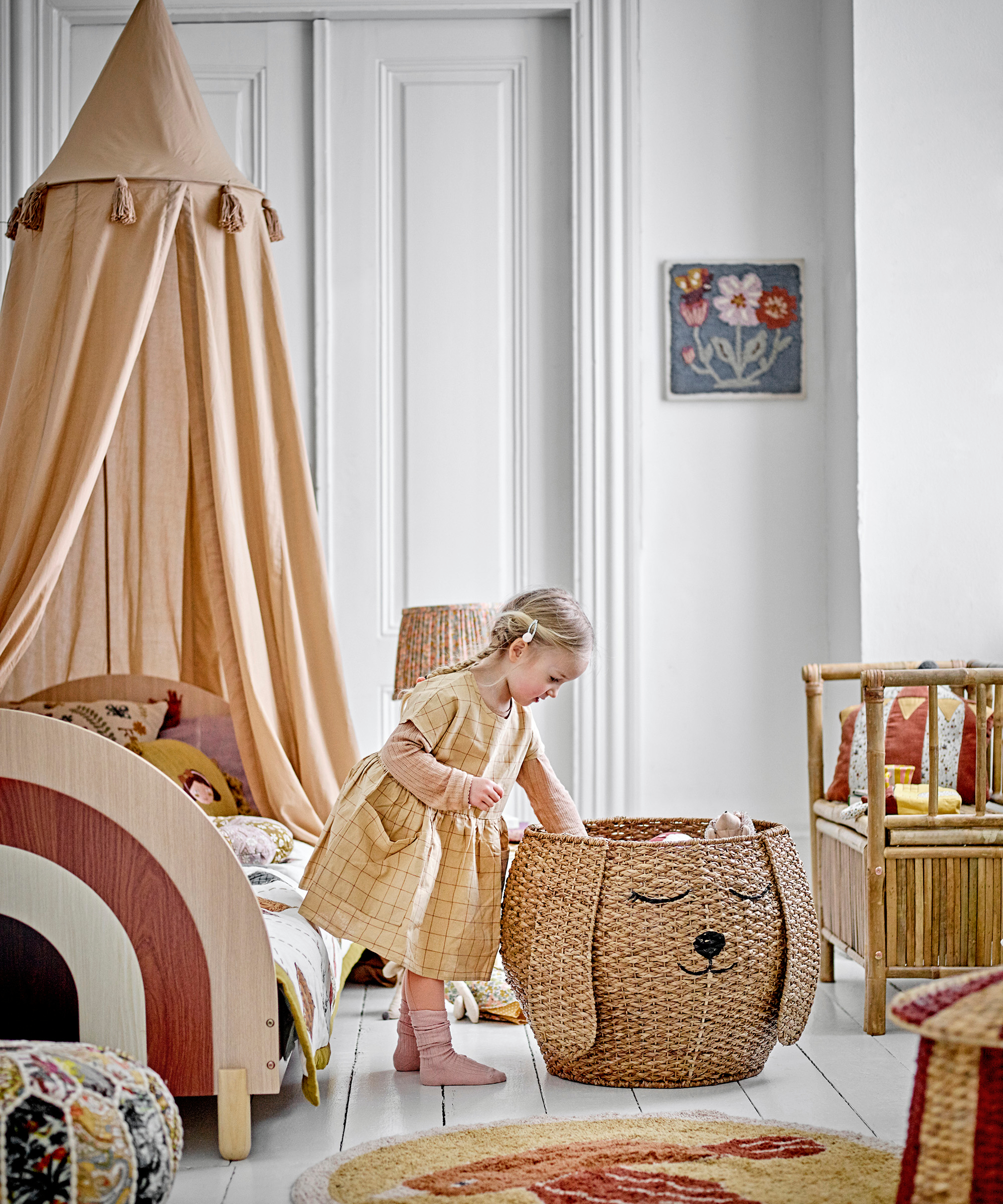 little girl in child's bedroom taking items out of rattan storage with a dog face