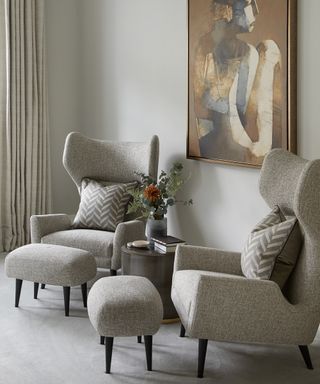 A bedroom furniture idea with two grey armchairs and matching footstools