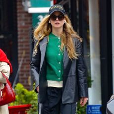 Jennifer Lawrence styles a green cardigan with a black leather blazer and track pants.