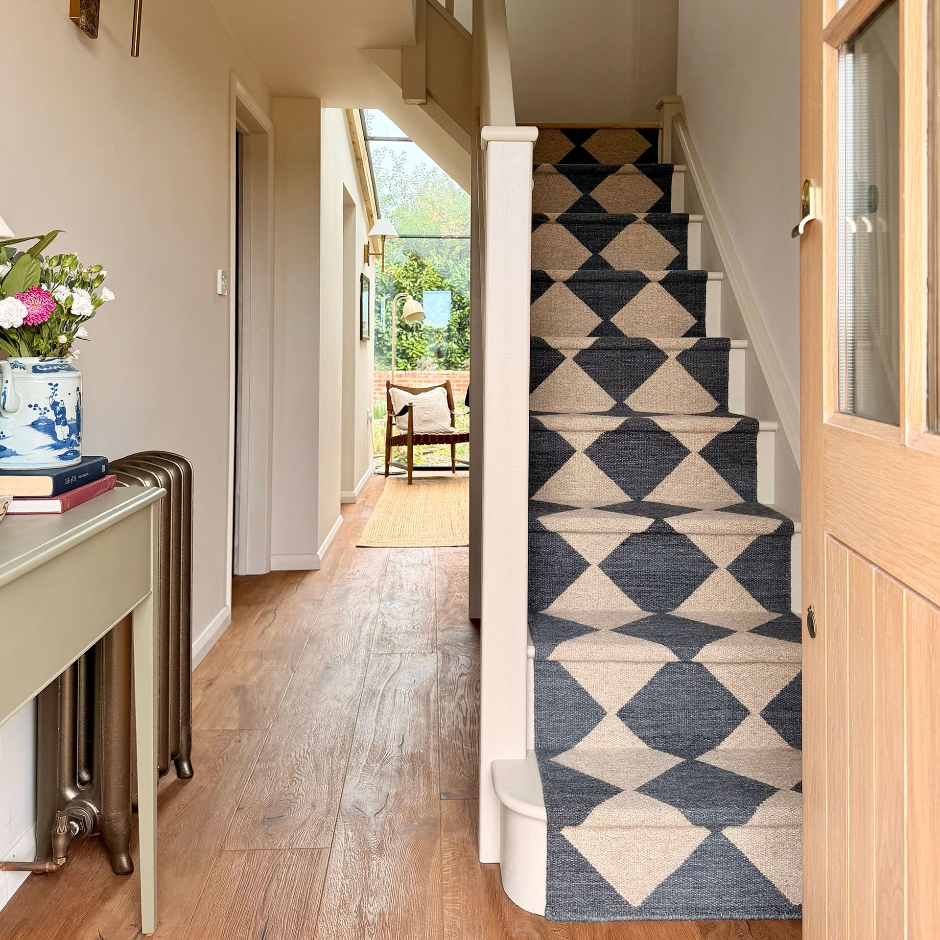 Entrance hall with wooden doors and floors and neutral and black chequered stair runner