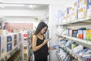 Thrush symptoms: A young woman scans drugs with her mobile phone at a pharmacy