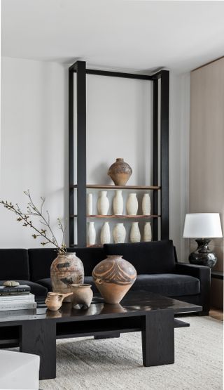 A set of black shelves decorated with a selection of ceramic vases