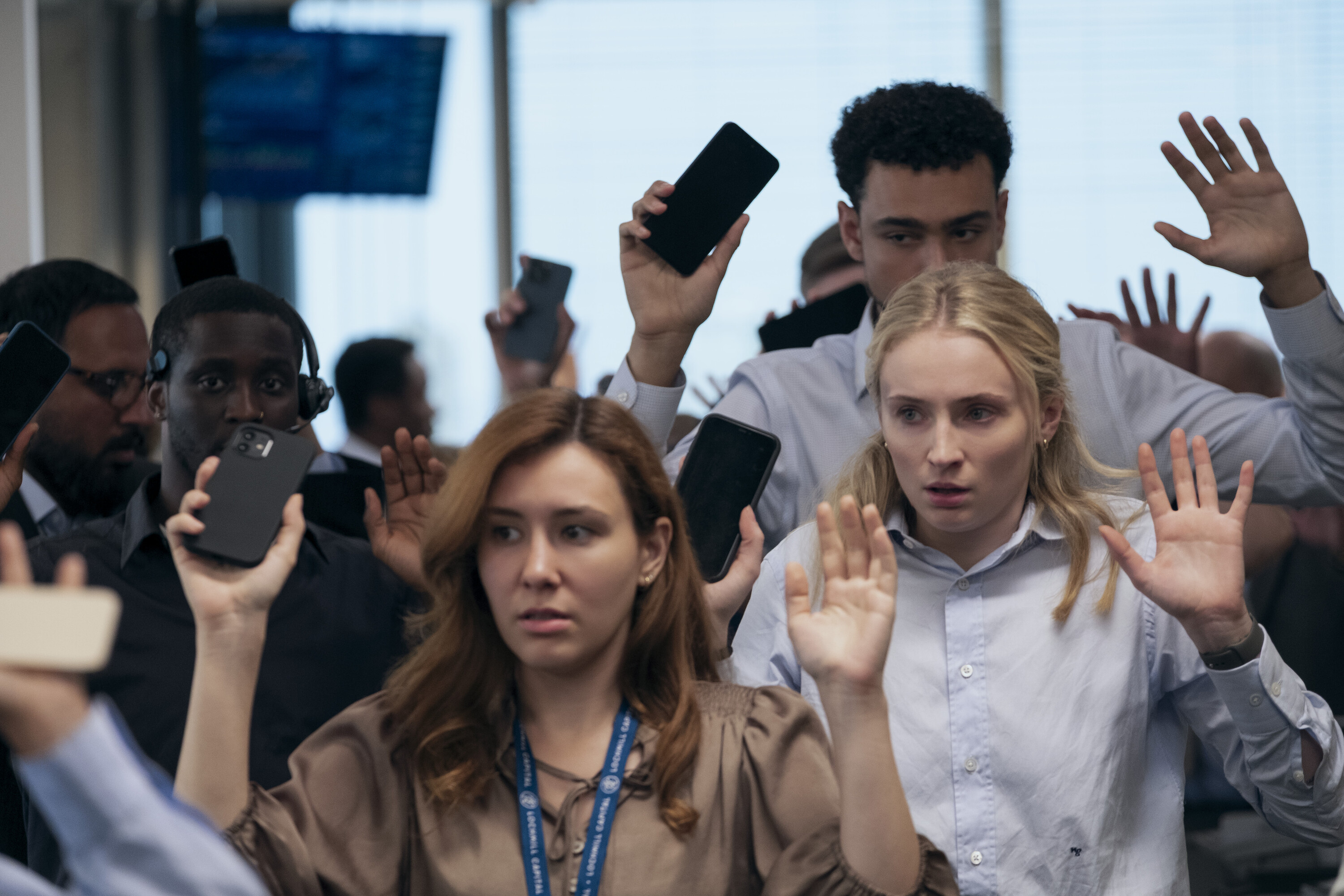 sophie turner as zara and archie madekwe as luke suck in a crowd being ushered into a hostage situation in an office building in a still from steal