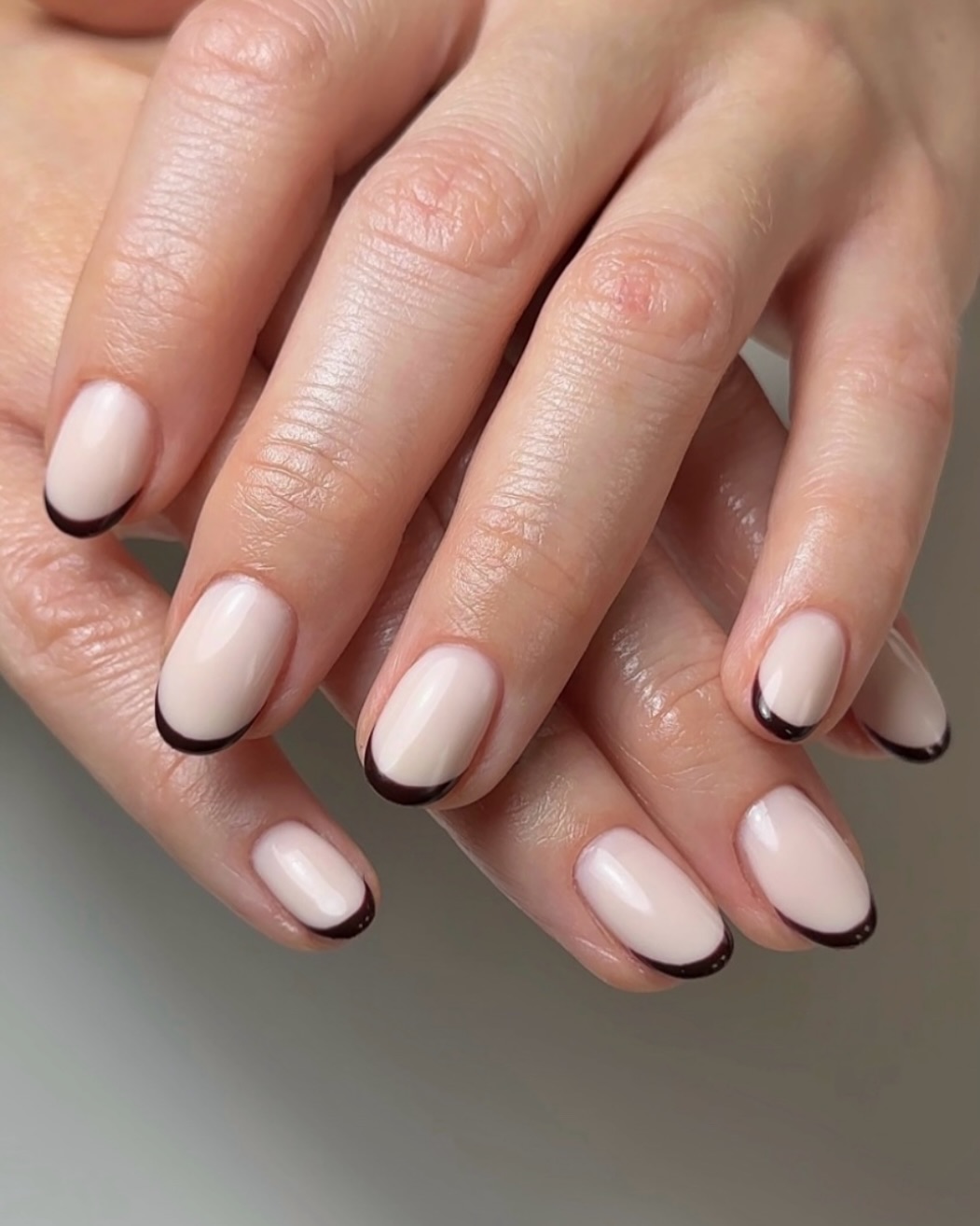 a person wearing nude nail polish with brown tips