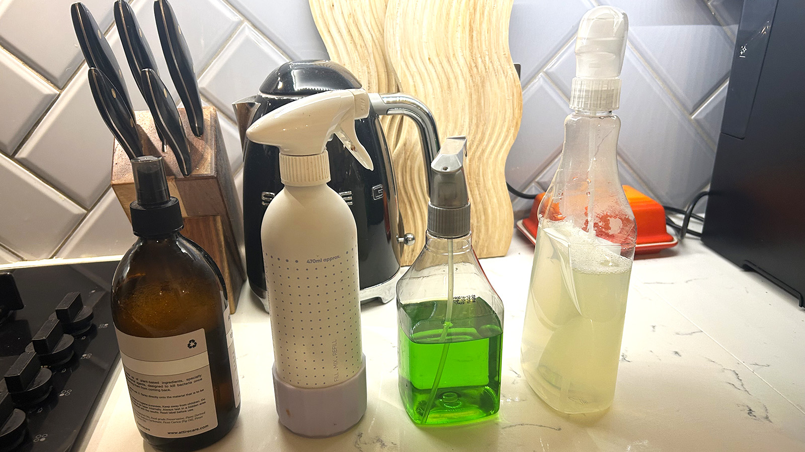 Homemade cleaning sprays lined up on a countertop