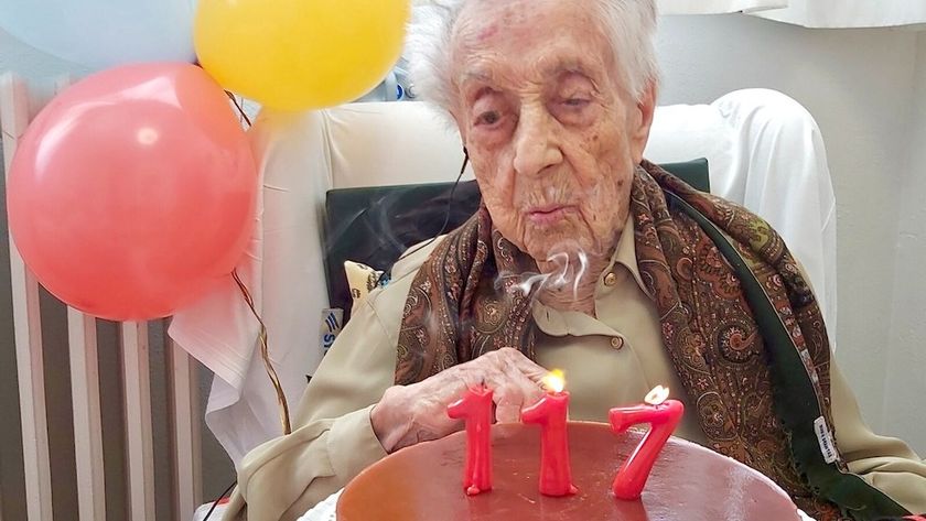 An elderly woman blows out candles shaped like the number 117 on her birthday cake 