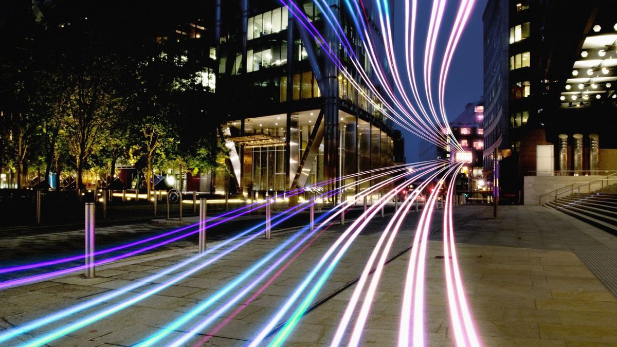 Bands of light flow towards the camera, across a dark street