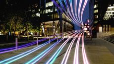 Bands of light flow towards the camera, across a dark street
