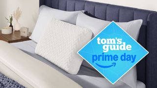 A close up of the head of a bed with three pillows resting against a headboard, the Tempur-Pedic Tempur-Cloud pillow is propped up in the front. A Tom's Guide Prime Day deals graphic to the right of the picture