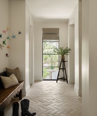 Tiled mudroom hallway with wooden bench, long window, foliage and bird wall feature