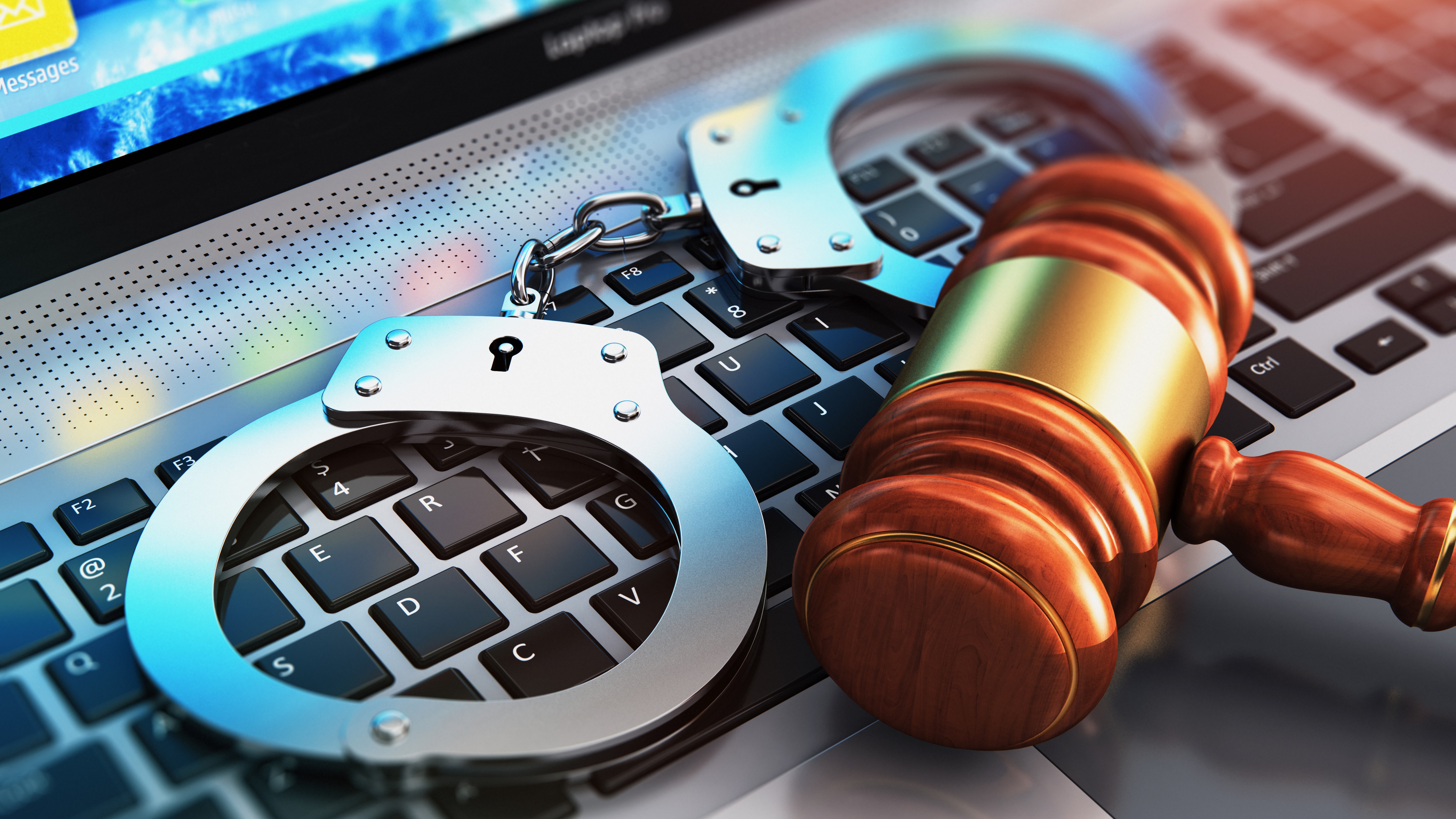 Handcuffs and gavel resting on the keyboard of a laptop PC.