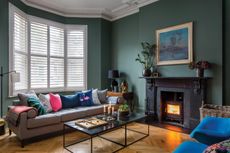 window treatments with white shutters in a dark living room with fire