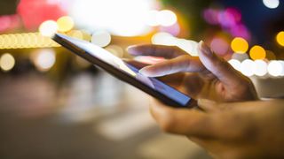 Hands holding smartphone with blurred lights in background