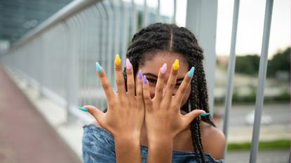 Teen showcasing multicolored long nails, fashion lifestyle concept.