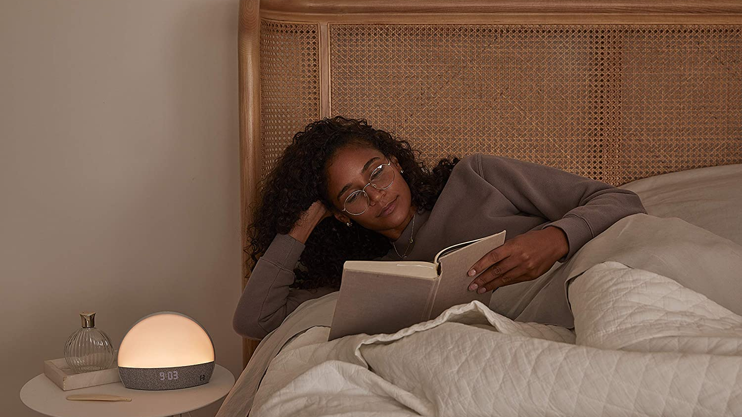 Eine Frau mit lockigem schwarzem Haar liest im Bett, um sich vor dem Schlafen zu entspannen