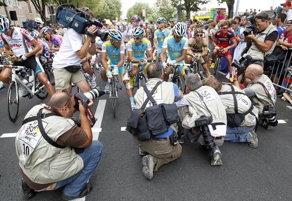 TV crew filming photographers taking pictures of riders captured by another photographer.