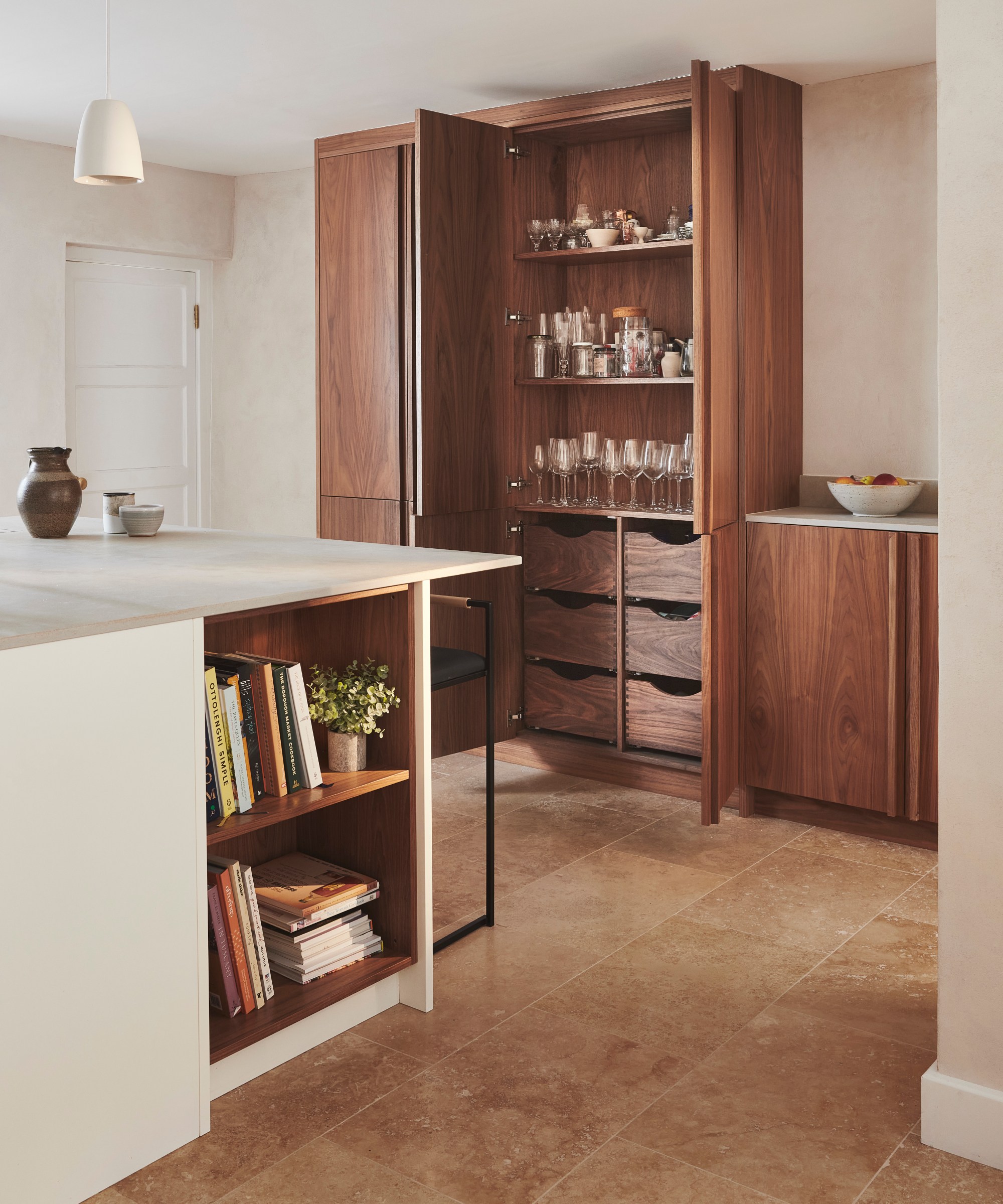 large floor to ceiling cabinets with drawers in lower half and shelving above with glasses, bottles and bar equipment