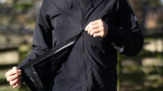 Albion Zoa Rain Shell jacket being unzipped using a two way zip from the bottom