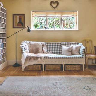 A living room with a wooden-frame sofa and storage baskets underneath it