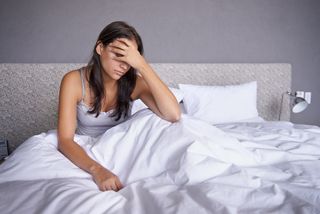 A woman suffers from a headache after sleeping on a moldy mattress