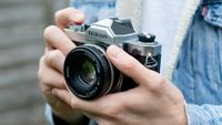 Man holding Nikon FM, wearing blue denim jacket 