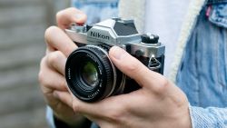 Man holding Nikon FM, wearing blue denim jacket