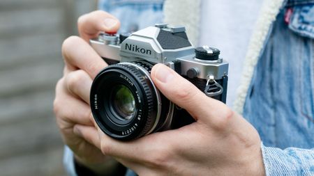 Man holding Nikon FM, wearing blue denim jacket 