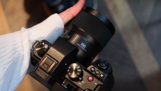 Panasonic Lumix S 100mm f/2.8 Macro lens attached to a Panasonic Lumic S5II and held in a hand