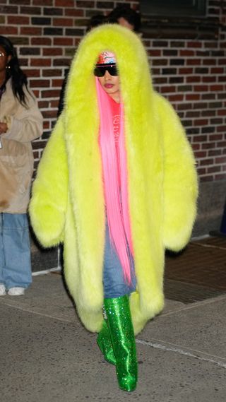 Nicki Minaj wearing a neon yellow long fur coat with emerald green knee-high boots