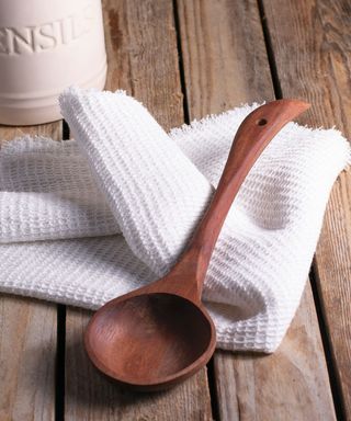 An acacia wood spoon on a white dish towel