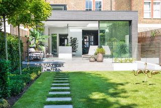 stepping stone ideas: modern garden with pathway across lawn towards house