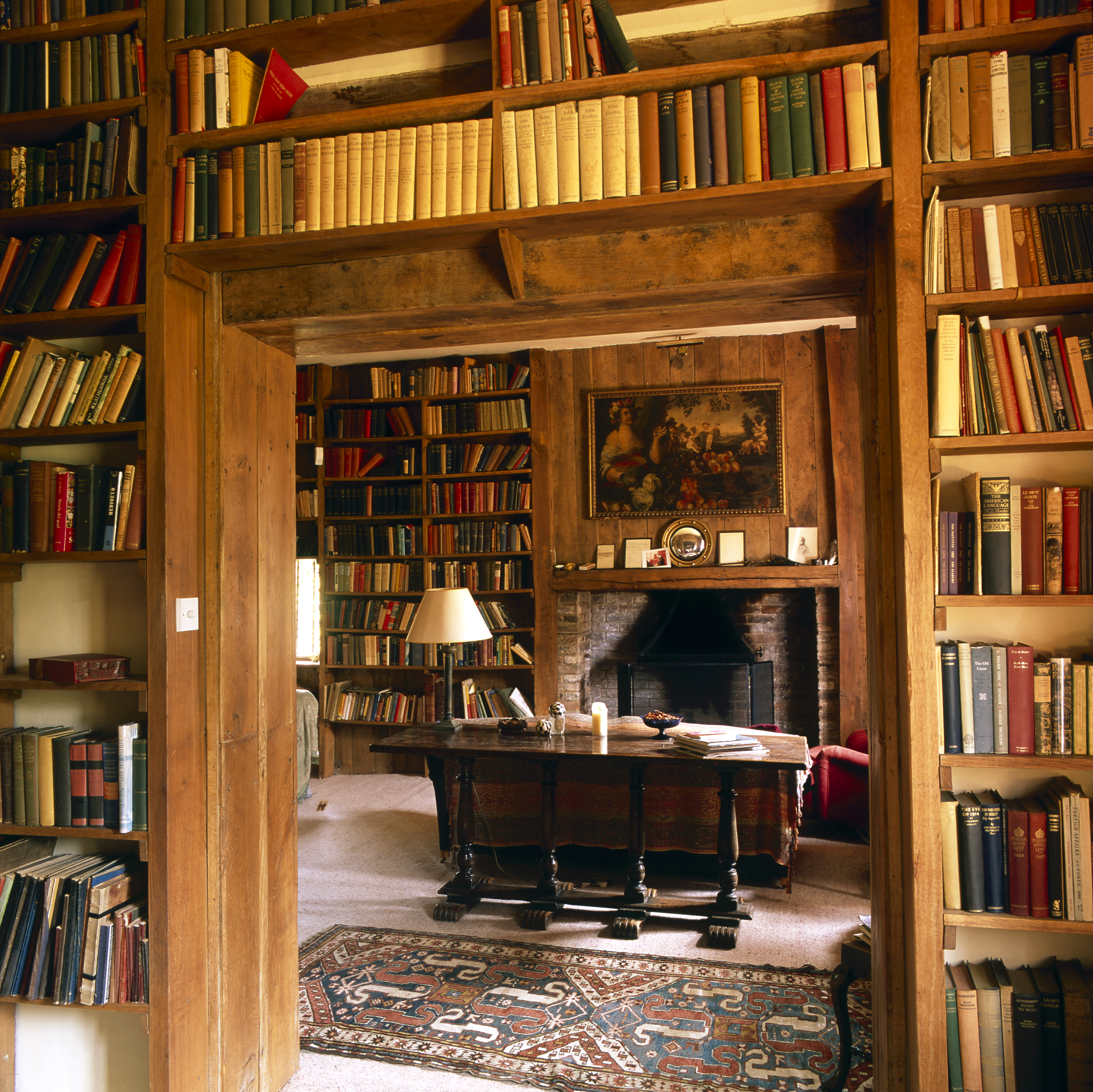 Small oak wood library with red sofas and a dark wood console table