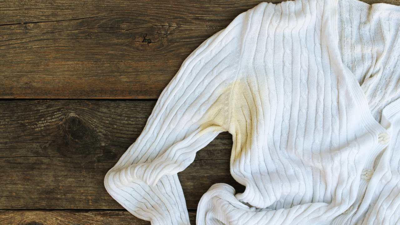 A white-hued long sleeve ribbed top with yellow sweat stains in the armpit.