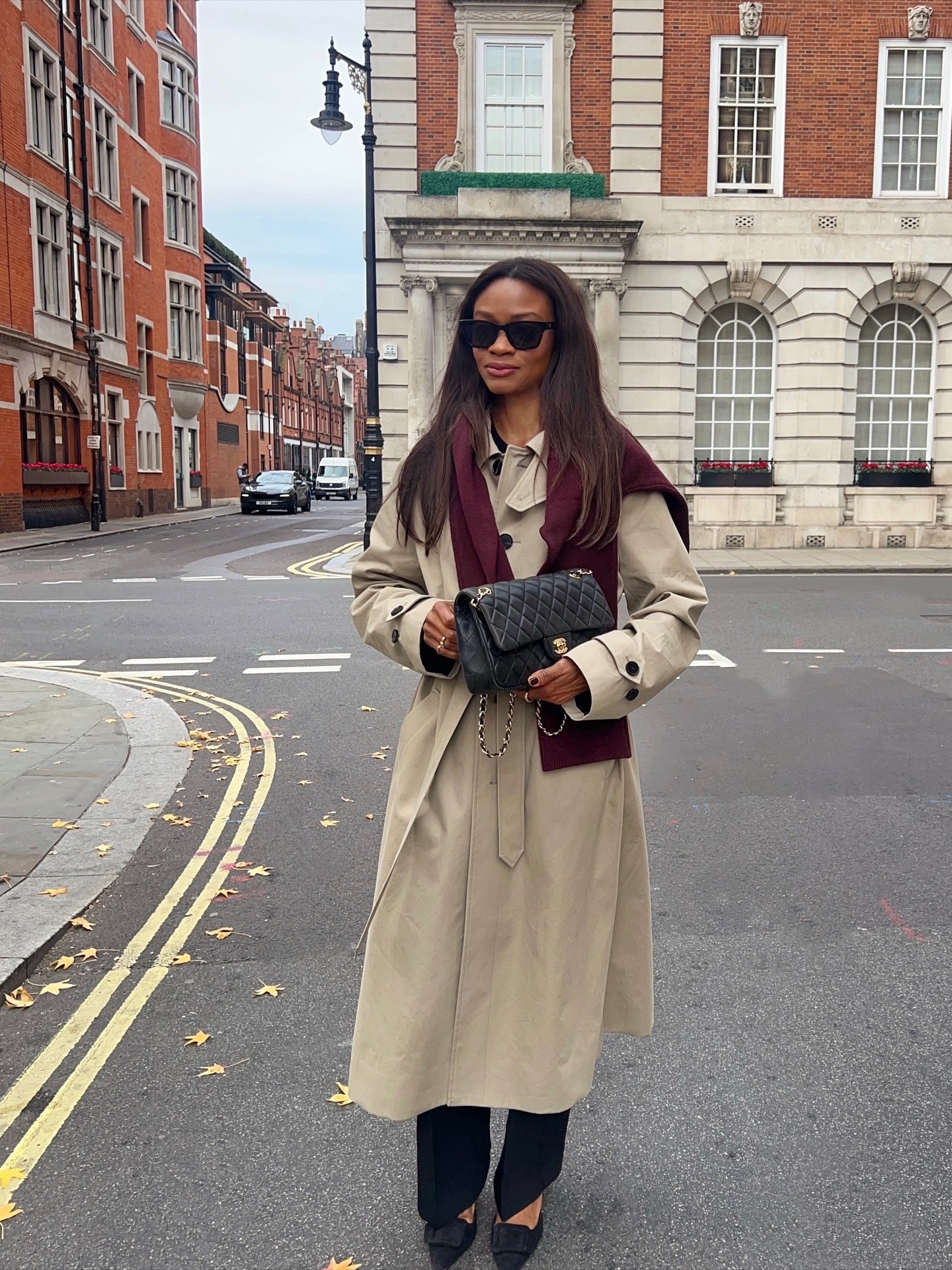 @symphonyofsilk wearing a trench coat, sweater, Chanel bag, and trousers
