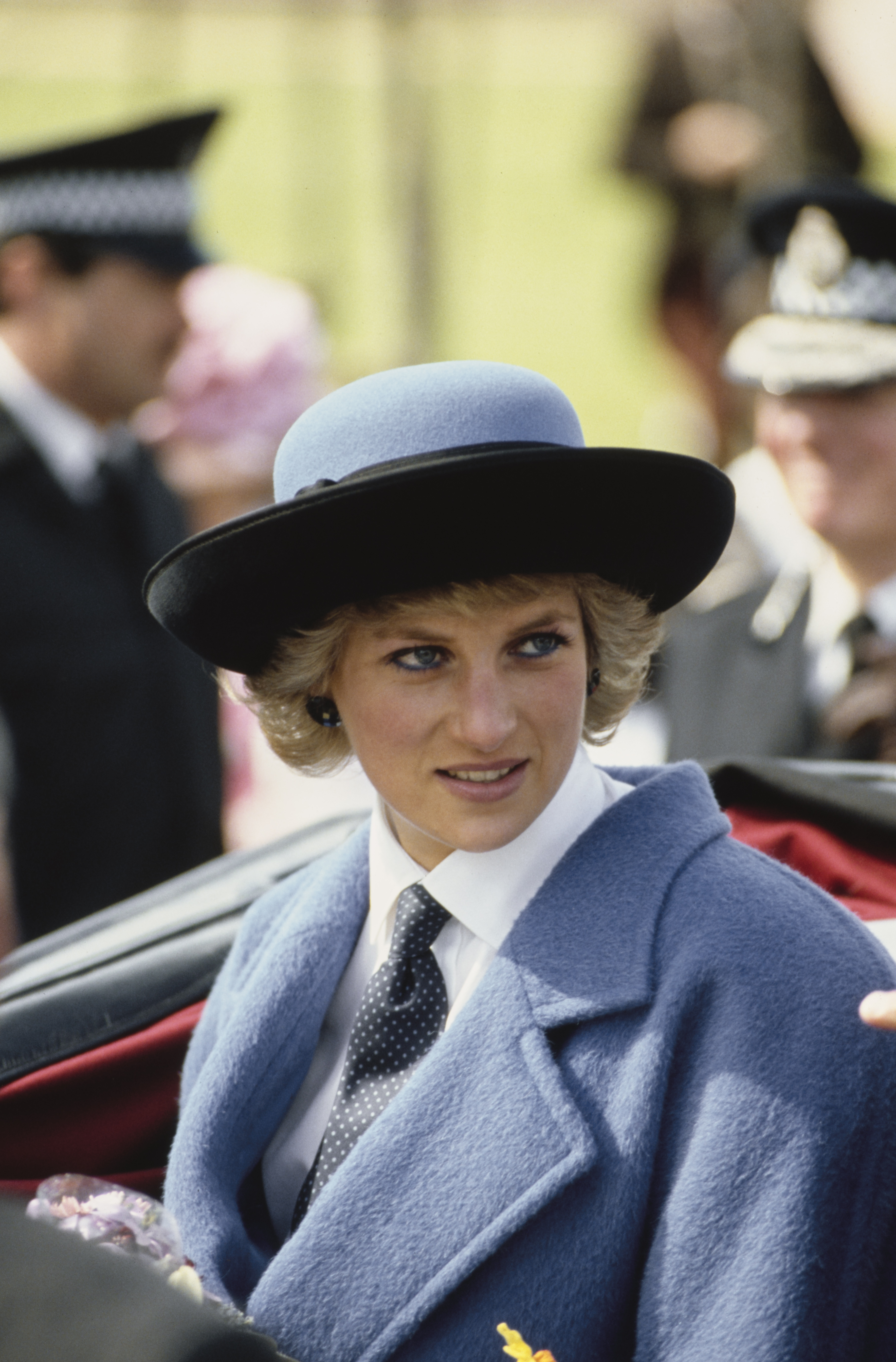 Princess Diana wearing a necktie and a blue coat in a carriage