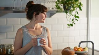 Woman drinking from a mug, relaxed in the kitchen and leaning against the kitchen counter