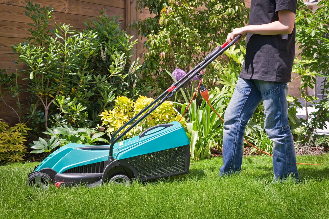 A boy mows a lawn.