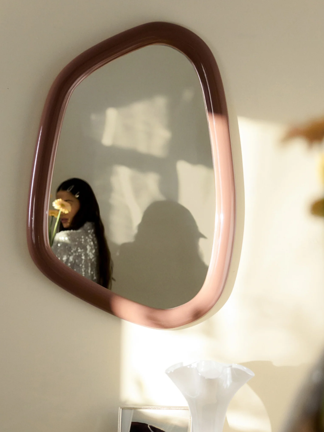 An organically-shaped wall mirror with a pale pink frame from Westwing