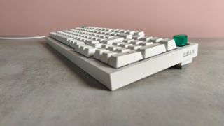 Three-quarter view of Logitech G316 X 98 on a desk with pink wall in background
