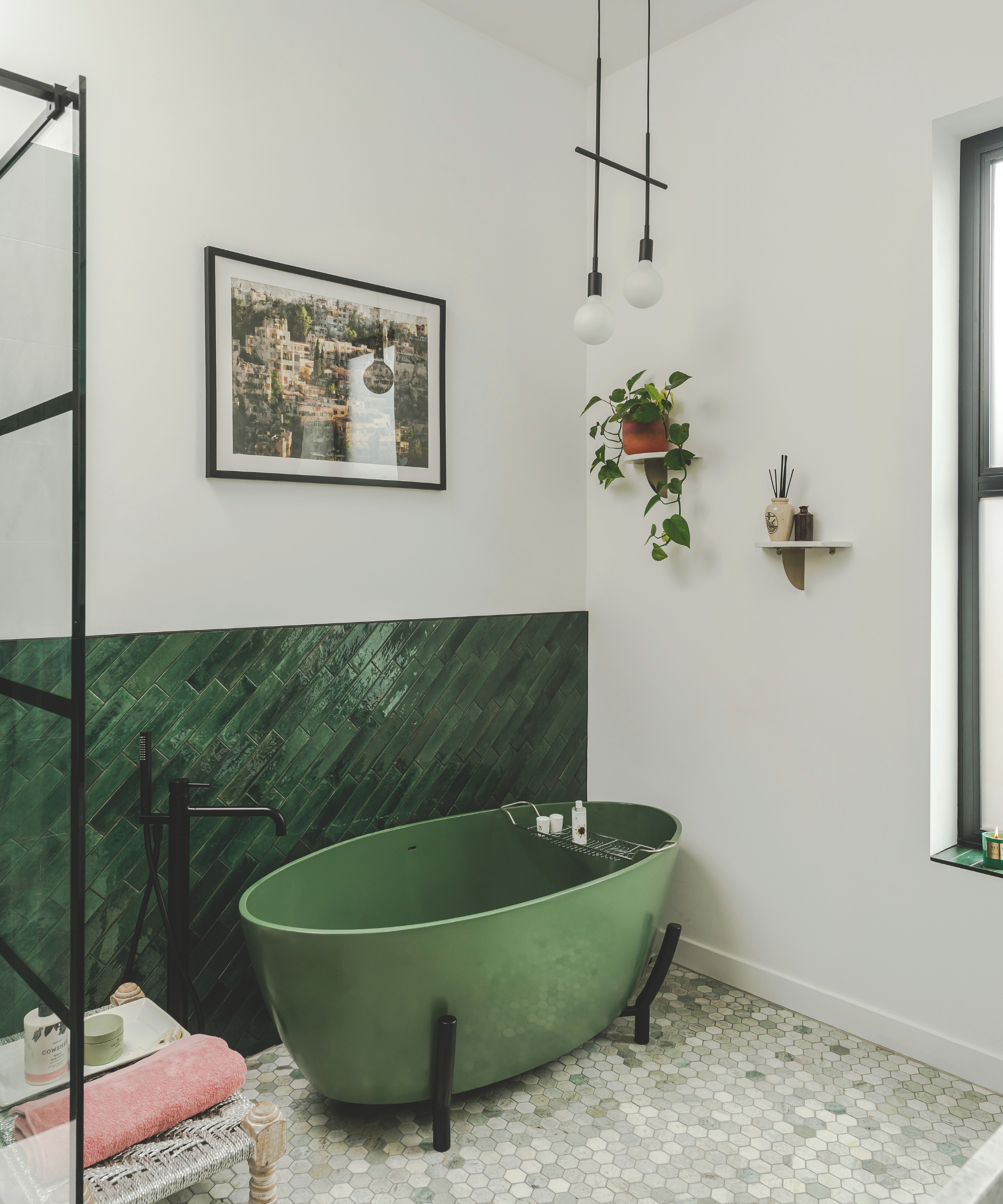 Bathroom with green freestanding bath with black legs and half wall green tiles