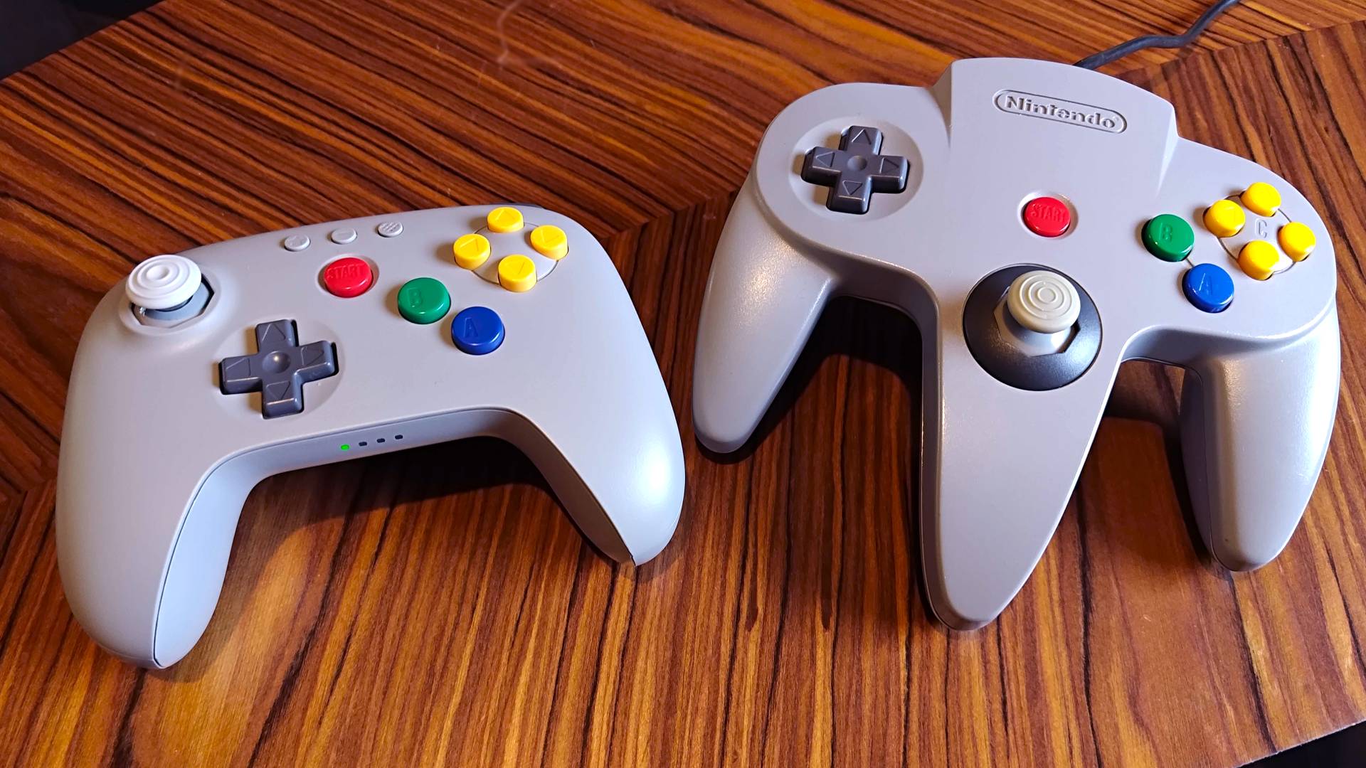 8Bitdo N64 controller on woodgrain table with original controller on right.