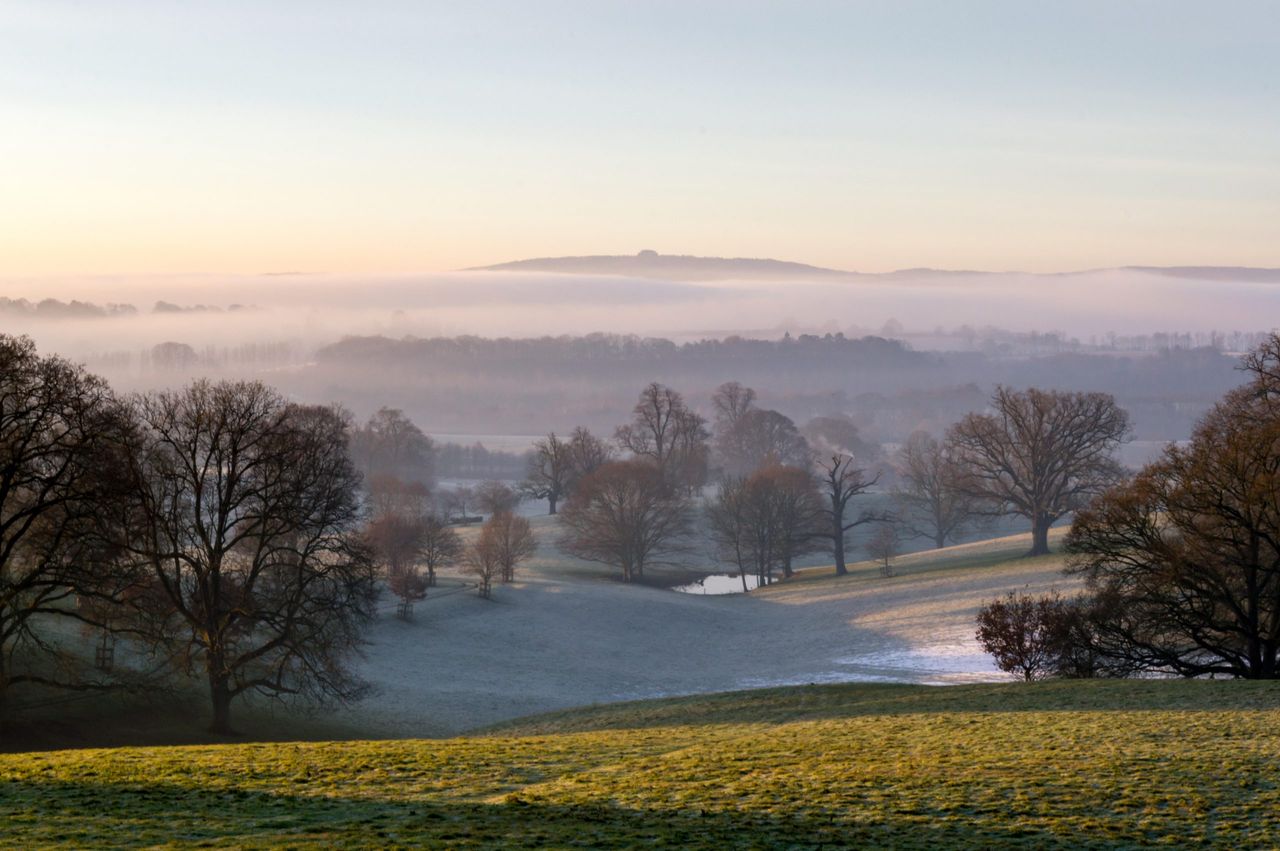 Sunrise over the english countryside on a misty winters day, looking out from the Malvern Hills towards May Hill, Gloucestershire.