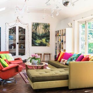 living space with large corner sofa and chairs bright cushions and wooden flooring