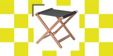 A folding stool with wooden legs and grey canvas on a green and white background.