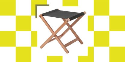 A folding stool with wooden legs and grey canvas on a green and white background.