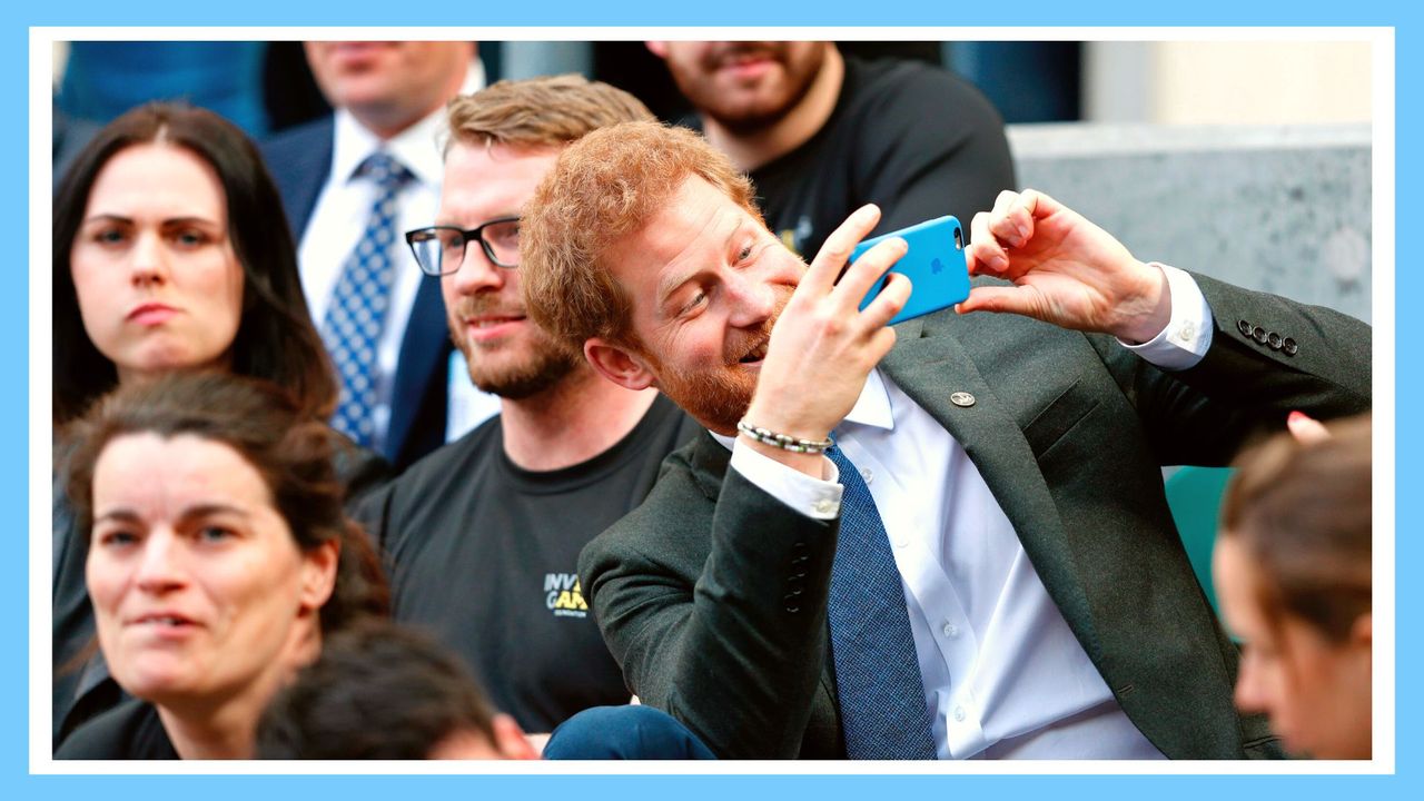 Britain&#039;s Prince Harry (R) uses a smartphone to take a photograph as he sits with competitors from the 2014 and 2016 Invictus Games in the crowd