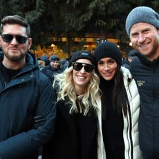 Prince Harry, Meghan Markle, Michael Buble and his wife posing in winter coats and hats outside in Whistler, Canada