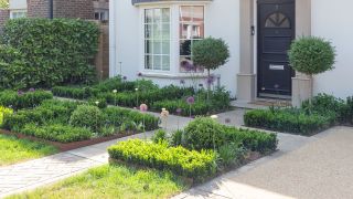 a front garden idea with a crossed path and green planting