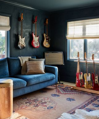 blue color drenched snug hobby room with large traditional rug and guitars on the wall